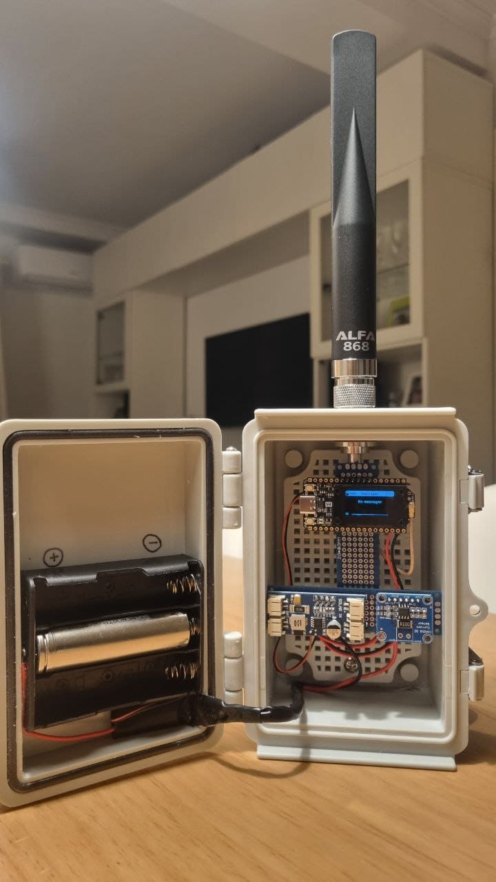 Nodo Meshtastic con antena ALFA 868 en caja estanca, con la tapa abierta mostrando la placa y las pilas